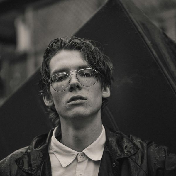 Person in a balanced pose against a dark, moody background.