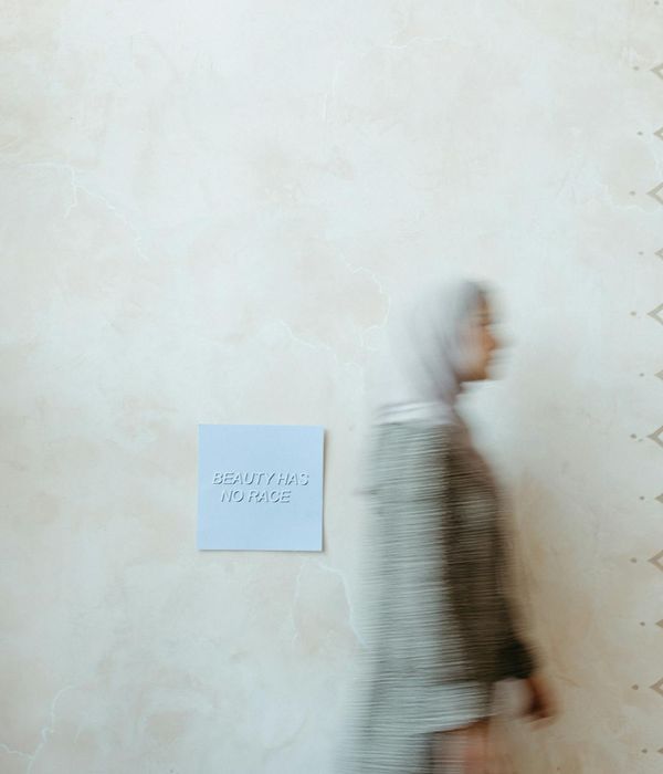 Woman performing a gentle, flowing movement in a minimalist space.